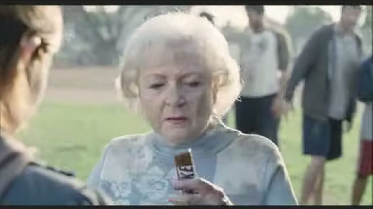 Бетти Уайт держит батончик Snickers на футбольном поле